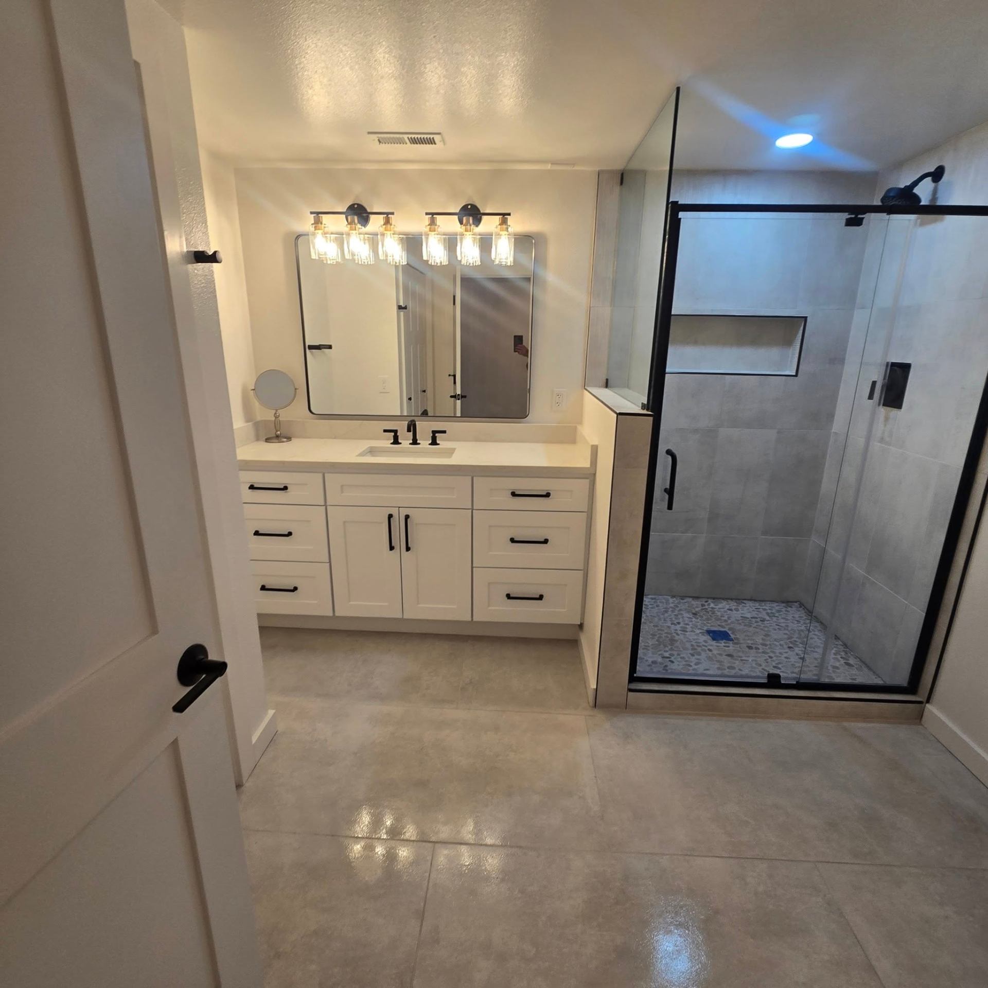 Bathroom remodel — master bath with white vanity, large mirror, and glass shower enclosure