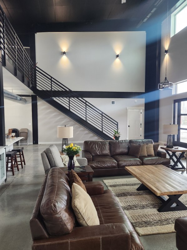 Custom home — two-story living room with leather sofas, steel staircase, and wall sconces