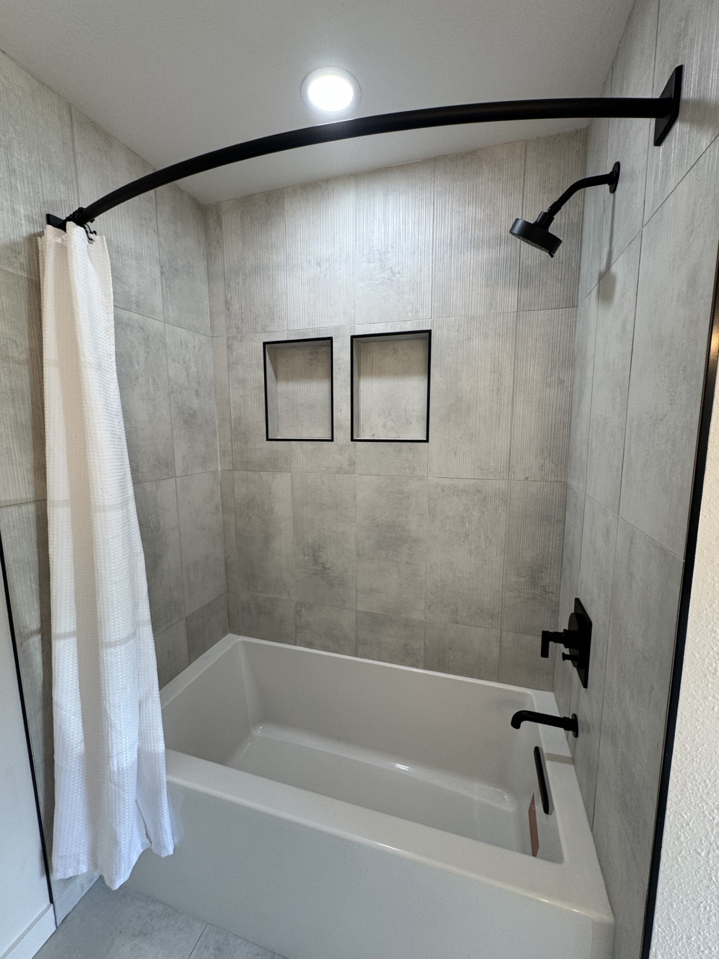 Bathroom remodel — tile tub-shower with twin recessed niches and matte black fixtures