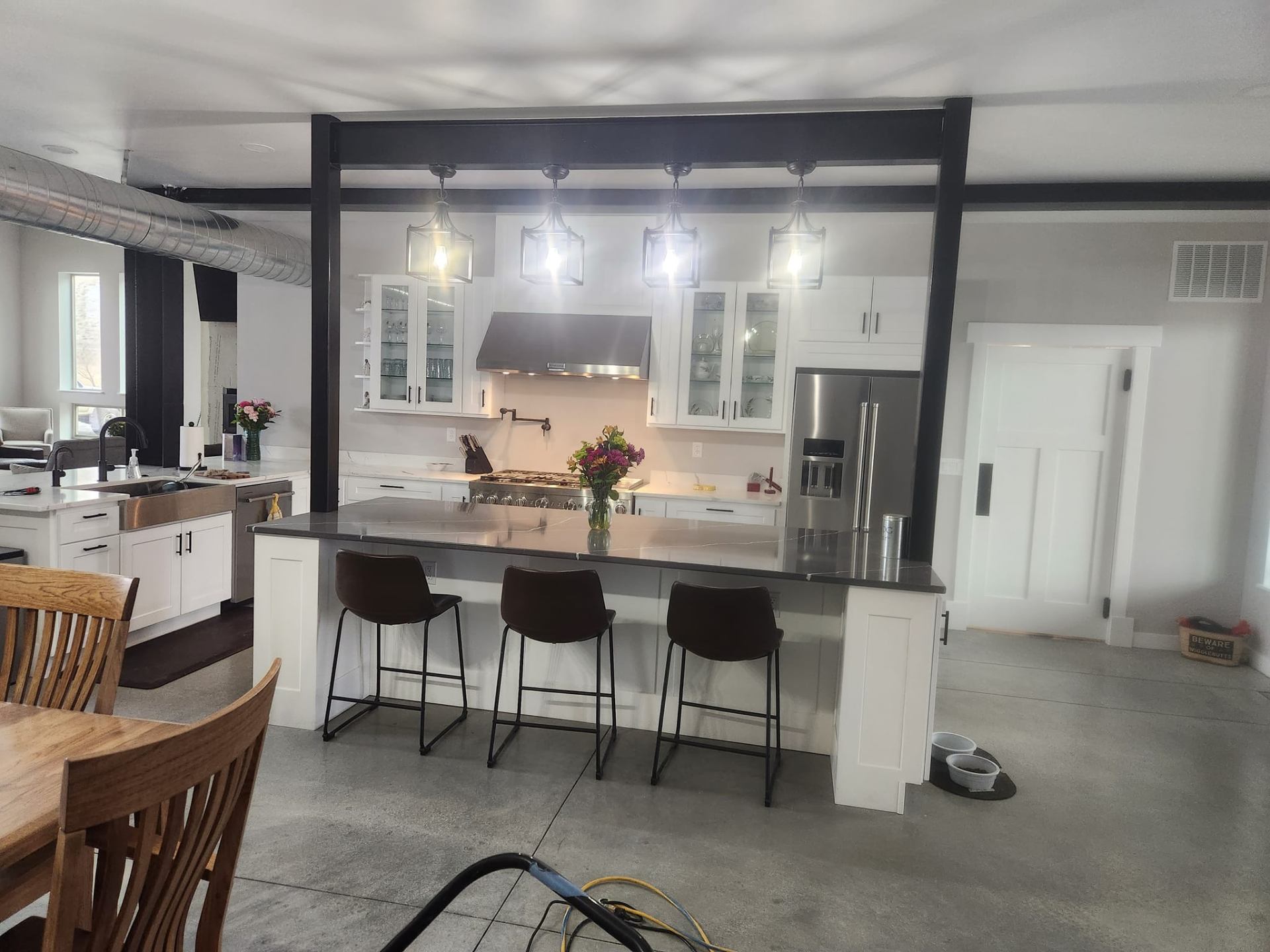 Custom home — finished kitchen with white shaker cabinets, quartz island, and exposed steel beams