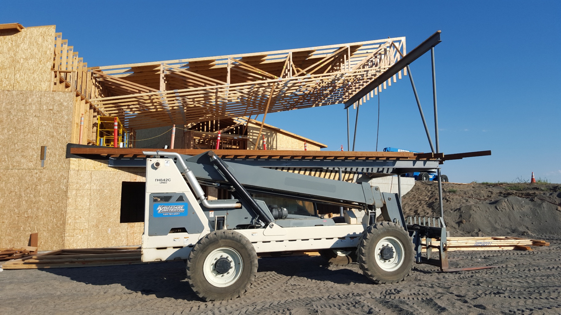 Knutson telehandler lifting roof framing into place