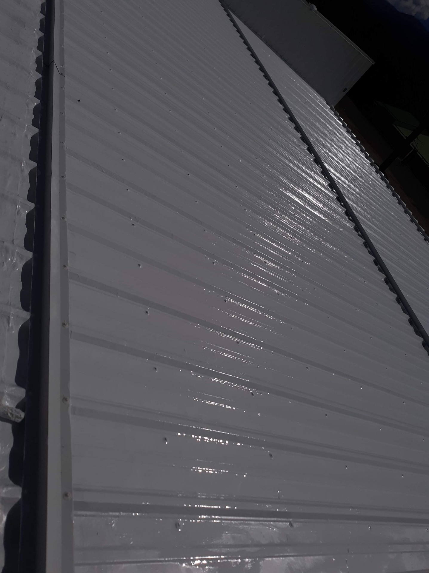 Fresh white roof coating on standing seam-style metal panels